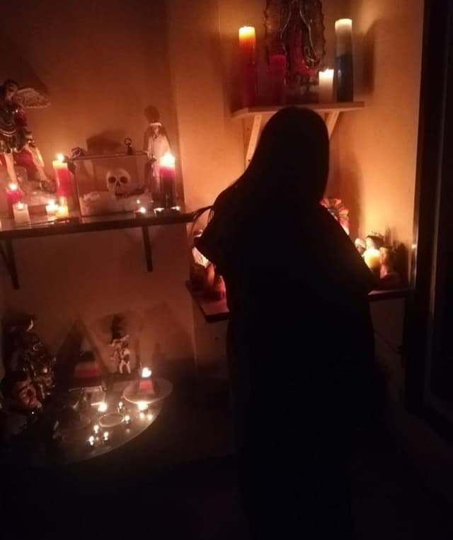 La Maestra preparando un hechizo de amor frente a su altar iluminado con velas