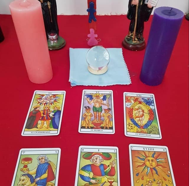 Altar de magia blanca con cartas del tarot, bola de cristal, santos y velas