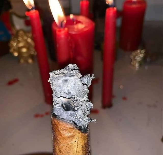 Lectura de tabaco junto a velas rojas en un trabajo de santería